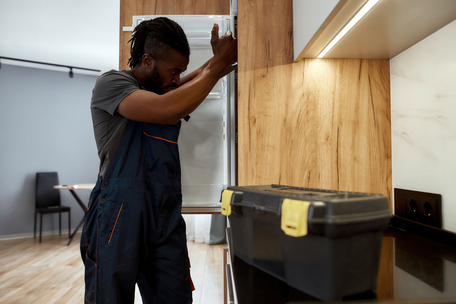 Concerned service man in workwear looking inside refrigerator